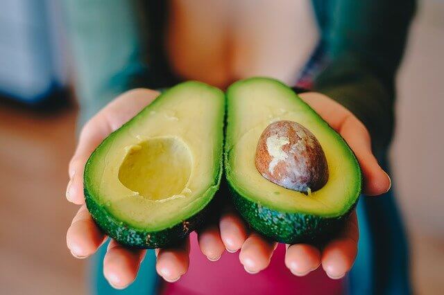 sliced avocado in hands