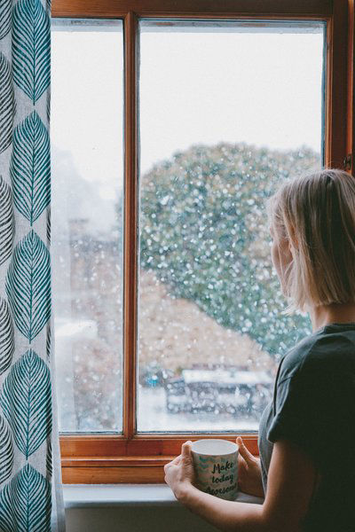 women with cup looking out the window