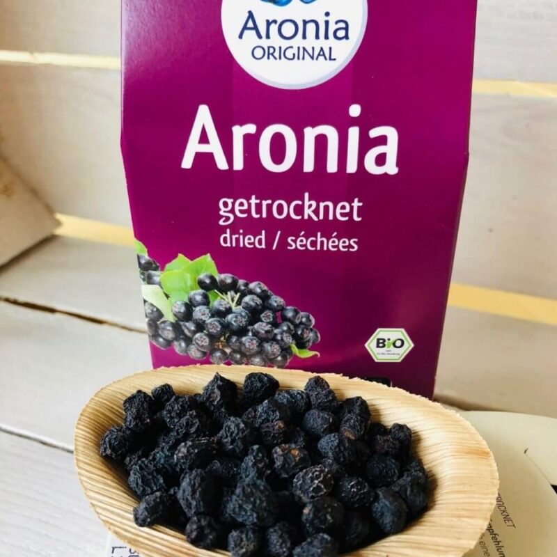 dried aronia berries on wooden spoon