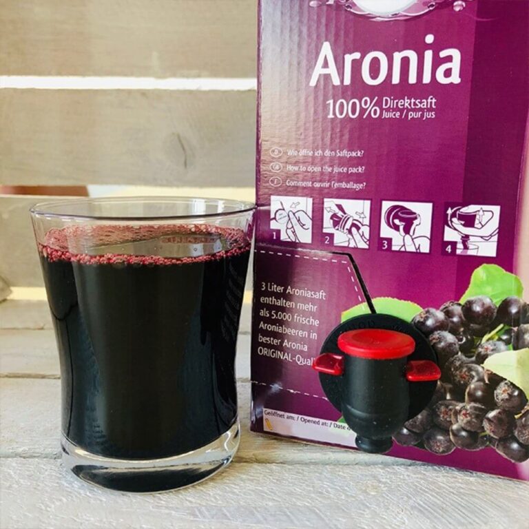 aronia berry juice in glass in front of aronia original 3 L aronia juice box